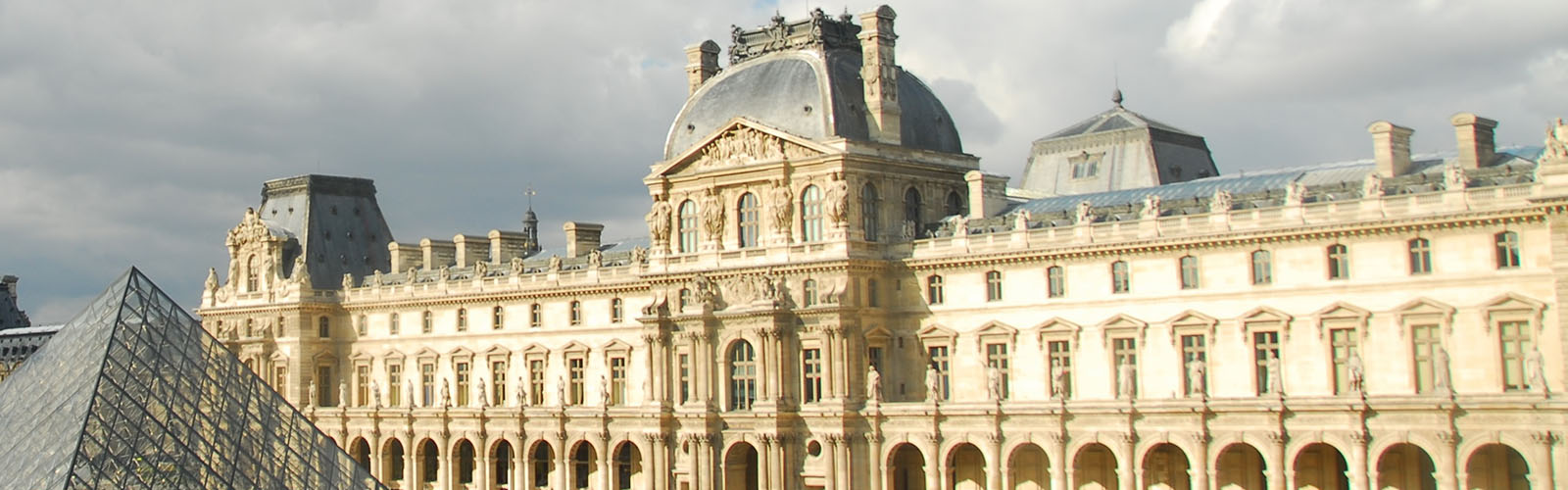 Exterior view of the Louvre. The iconic glass pyramid is off to the side.